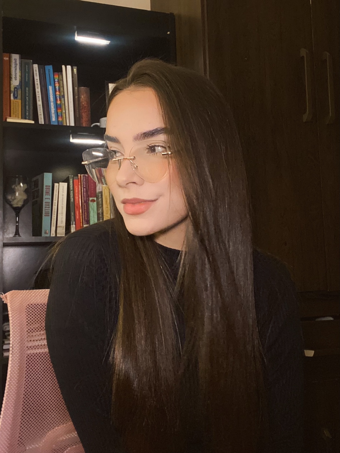Larissa Pomini diante de sua estante de livros